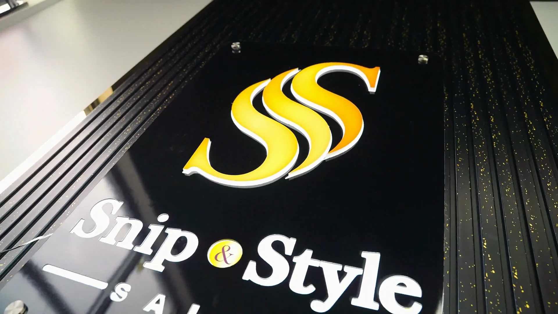 The illuminated Snip & Style sign on the fluted feature wall at the front of the salon.